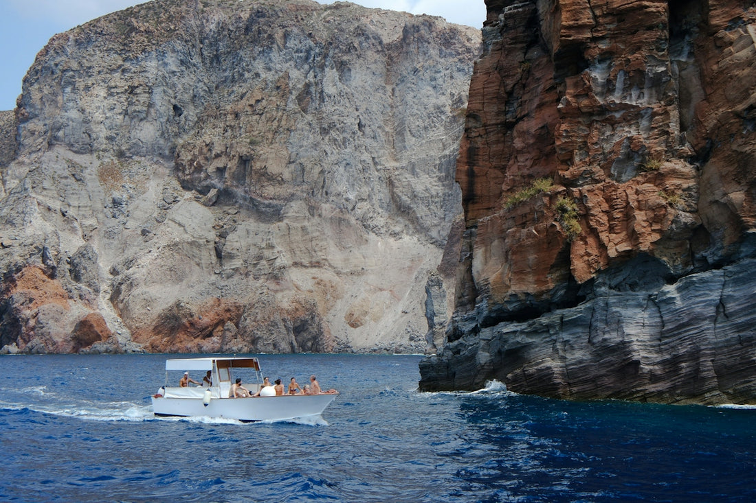 people in boat on body of water near brown rock mountains