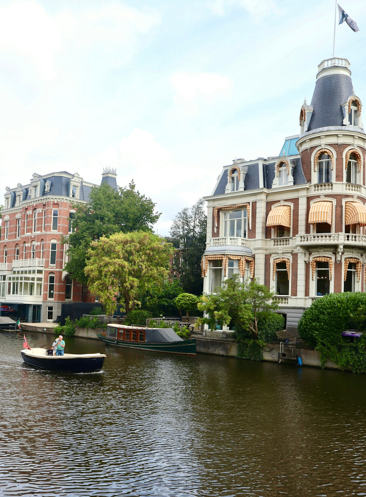 Boat on canal passing ornate buildings in amsterdam