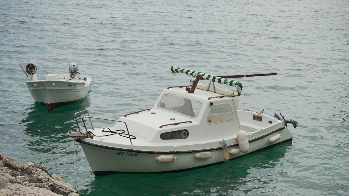 Two white boats floating on calm, clear water.