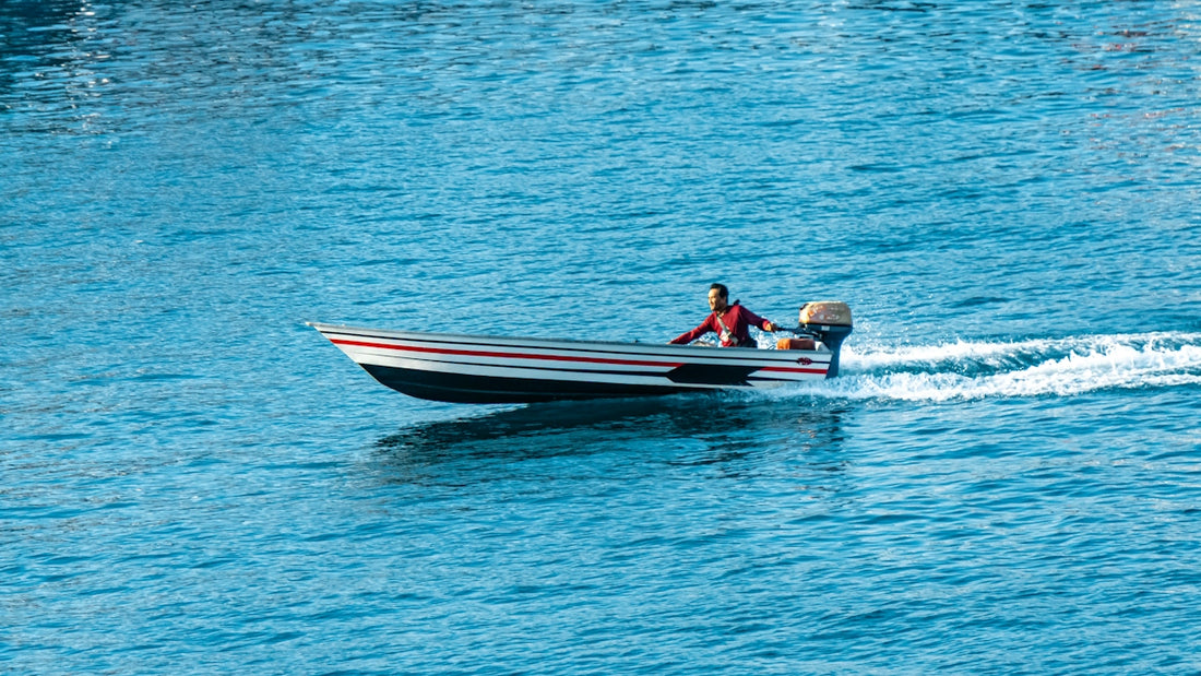 A person in a small boat speeds across blue water