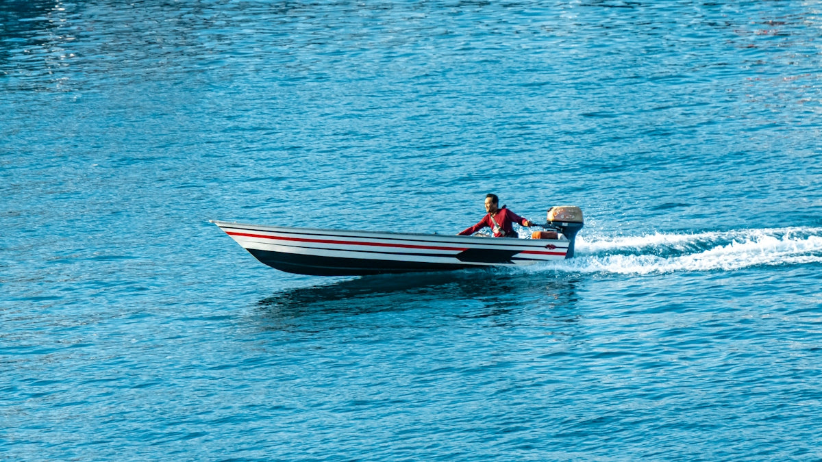 A person in a small boat speeds across blue water