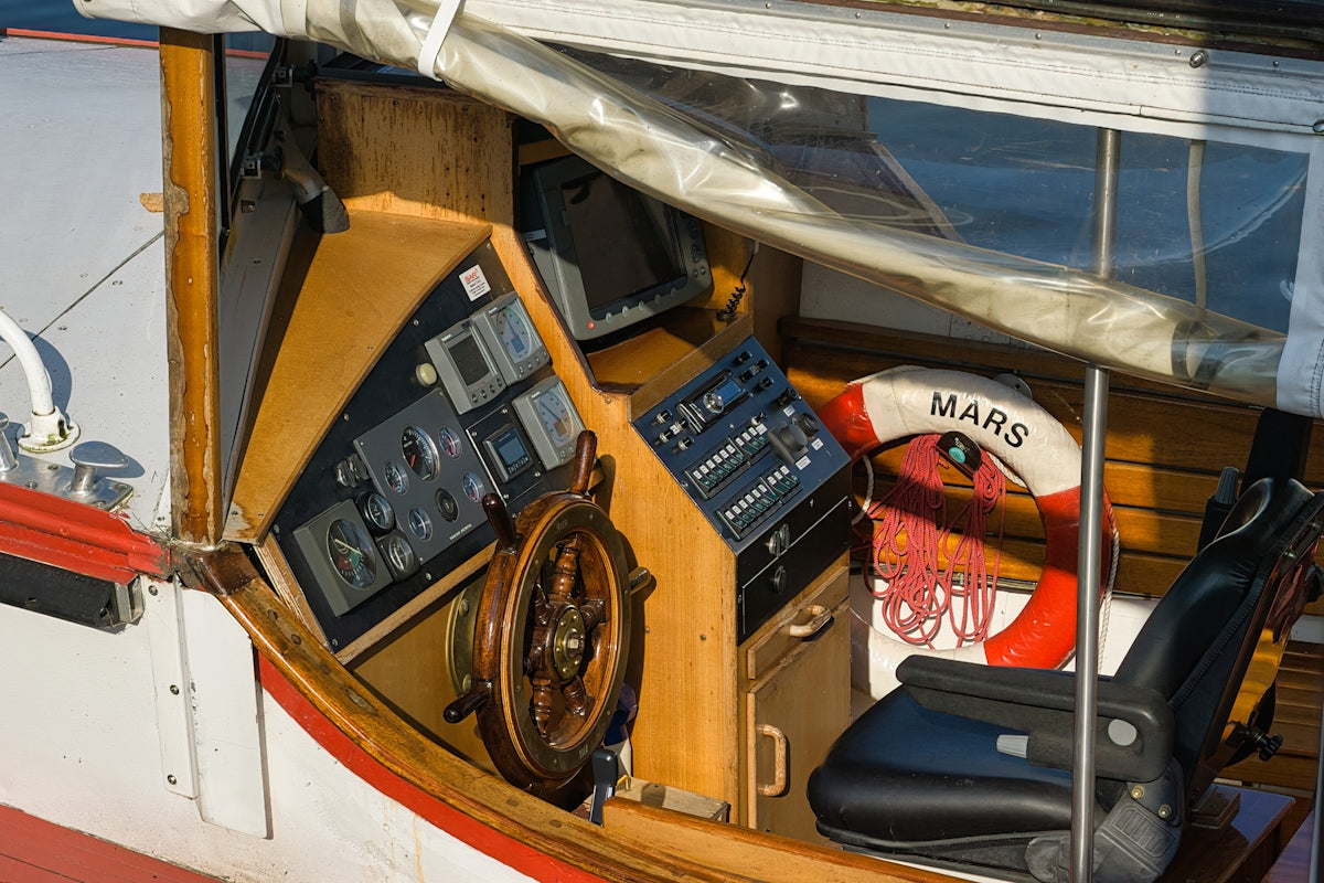 Wooden ship's wheel and control panel on a boat.