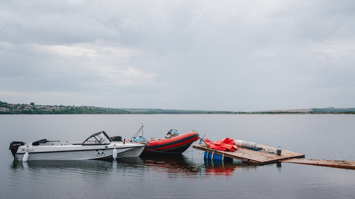 Three boats moored at a wooden jetty on a lake.