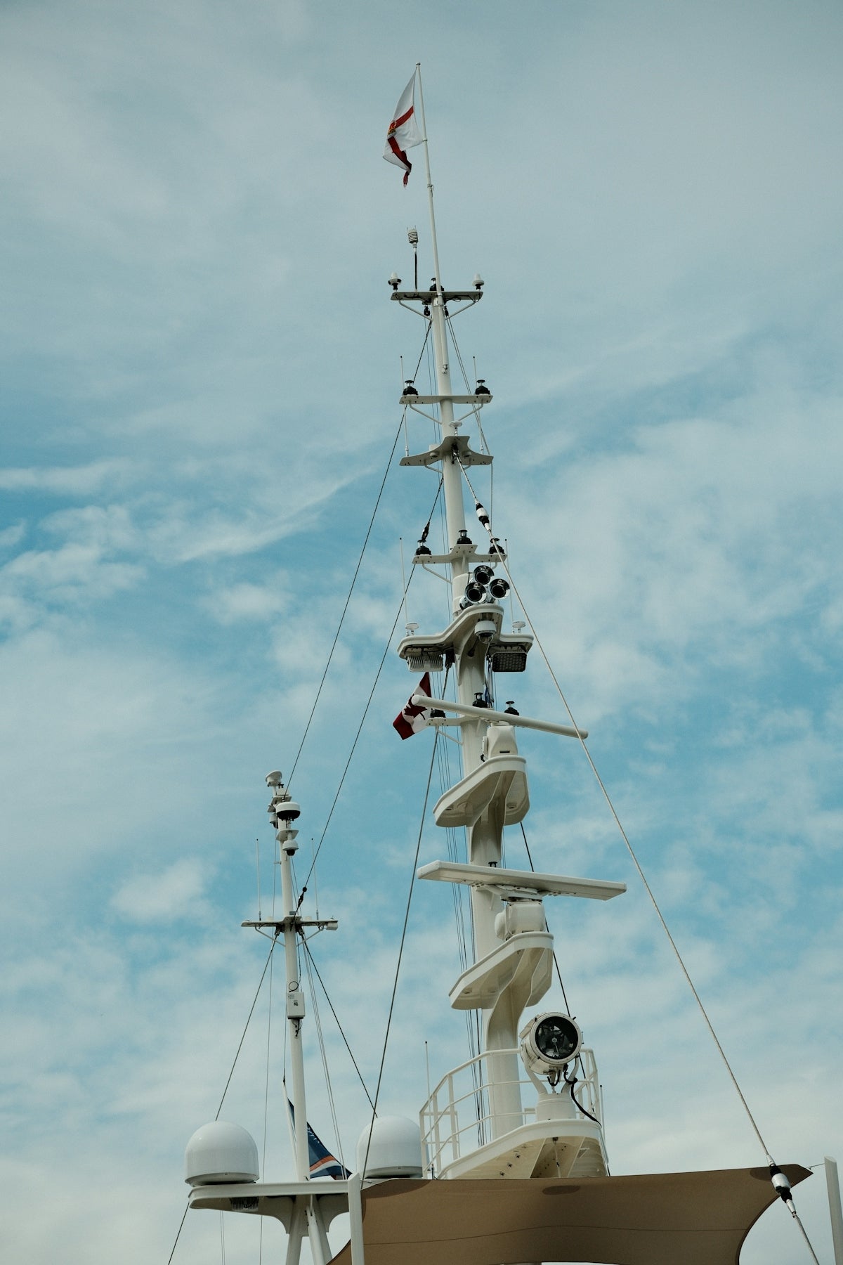 Tall mast of a yacht with radar and communication equipment.